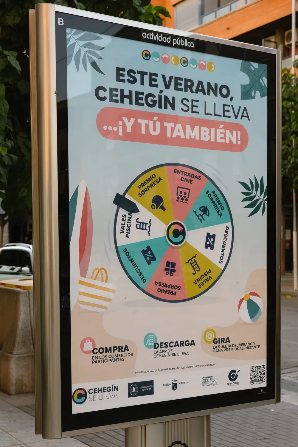 Mupi en una calle de Cehegín con el cartel de la campaña de verano de Cehegín se lleva: una ruleta de premios y tres pasos, comprar en los comercios participantes, descargar la app y girar la ruleta.
