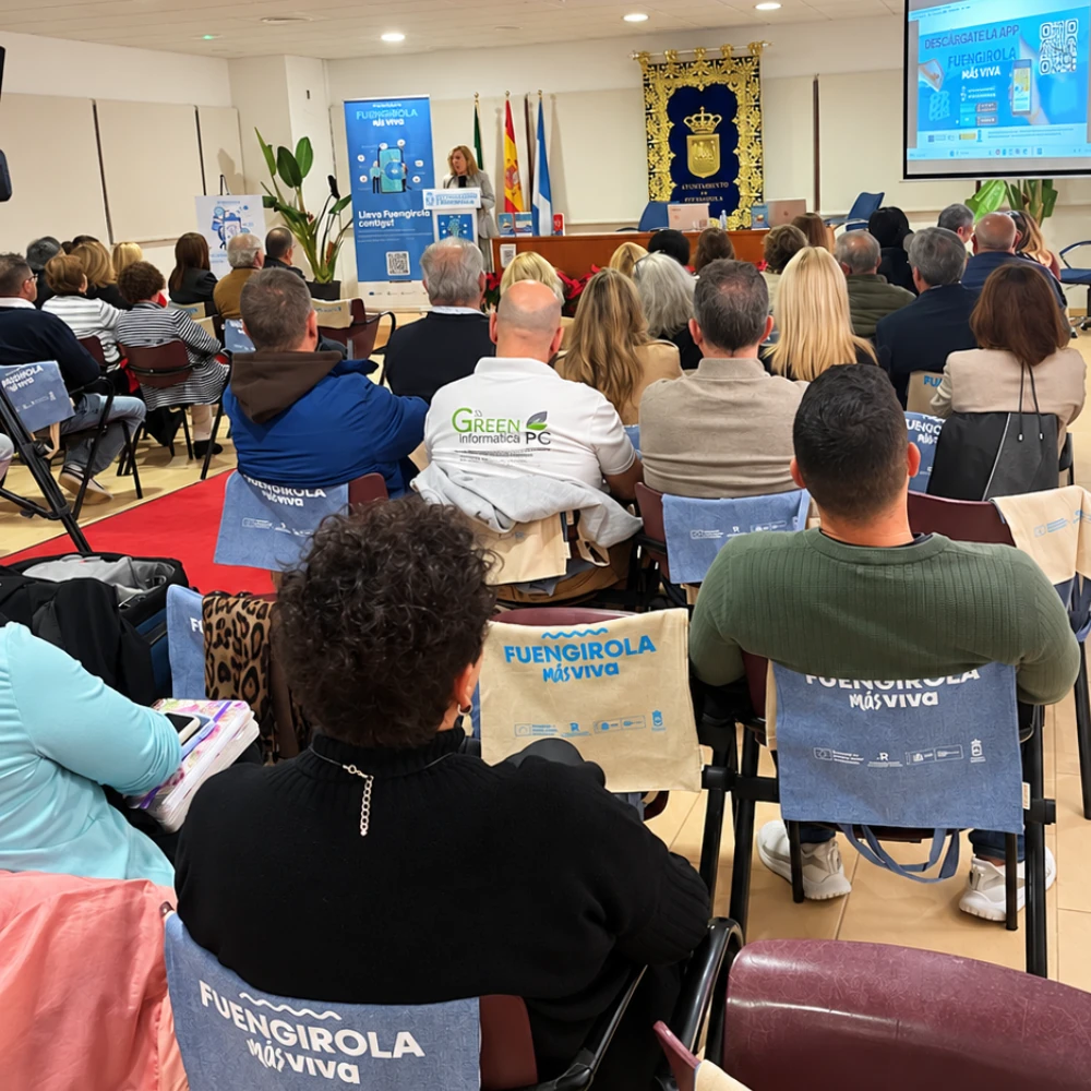 Presentación de Fuengirola Más Viva en una sala municipal, con una ponente ante los asistentes y la imagen del proyecto en la pantalla.